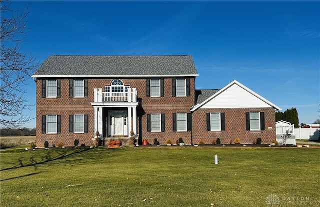 colonial inspired home with a front yard and a balcony