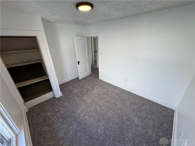 unfurnished bedroom featuring dark colored carpet and a textured ceiling