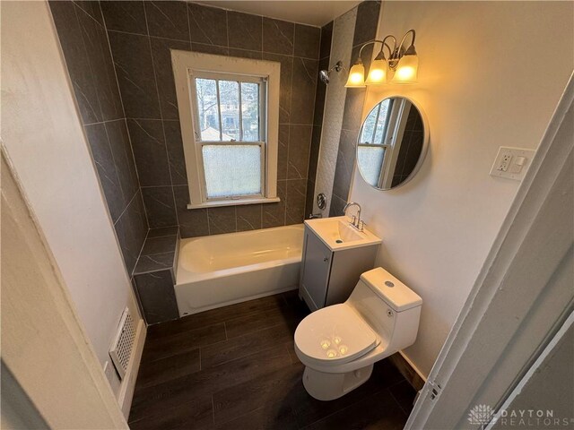 full bathroom with tiled shower / bath combo, wood-type flooring, vanity, and toilet