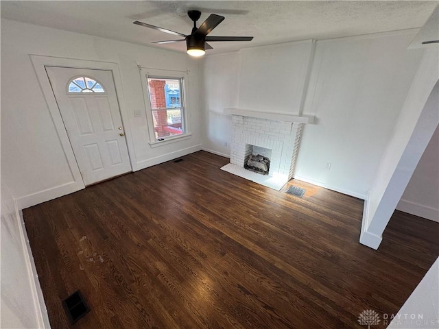 unfurnished living room featuring dark hardwood / wood-style flooring, a brick fireplace, and ceiling fan