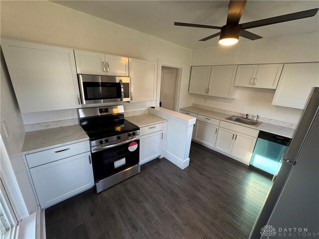 kitchen with appliances with stainless steel finishes, white cabinetry, sink, ceiling fan, and dark wood-type flooring