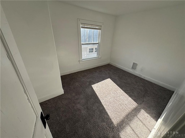 spare room featuring dark colored carpet