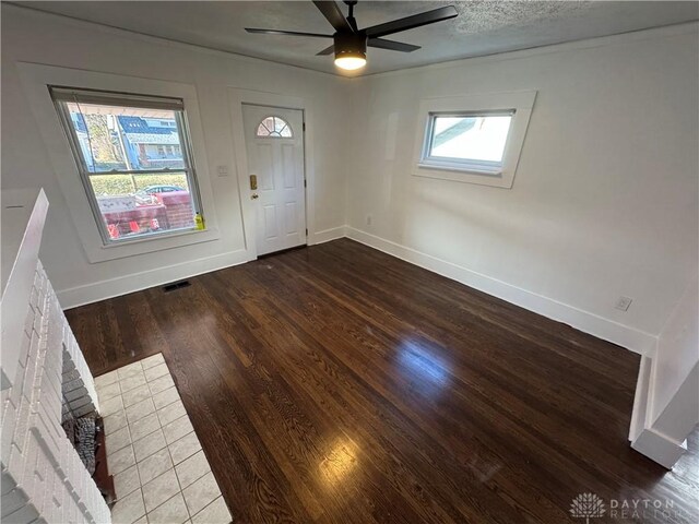 foyer with a brick fireplace, wood-type flooring, and ceiling fan