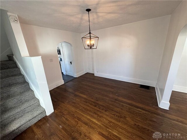 unfurnished dining area with a notable chandelier and dark hardwood / wood-style flooring