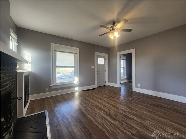 unfurnished living room featuring ceiling fan, dark wood-type flooring, and a brick fireplace