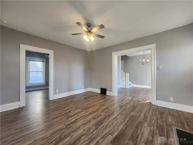 empty room with dark hardwood / wood-style floors and ceiling fan with notable chandelier