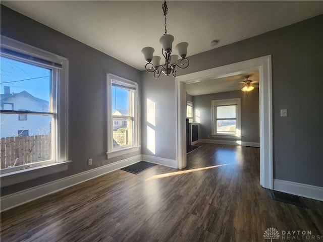 unfurnished dining area with dark hardwood / wood-style flooring and ceiling fan with notable chandelier