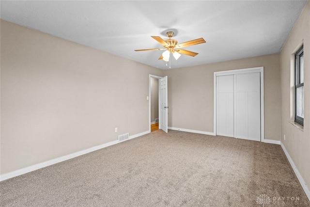 unfurnished bedroom with ceiling fan, carpet flooring, visible vents, baseboards, and a closet