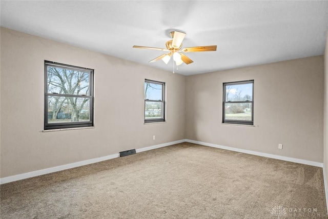 carpeted empty room with ceiling fan, visible vents, and baseboards