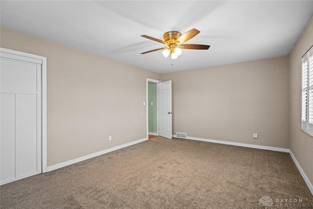 carpeted spare room with a ceiling fan, visible vents, and baseboards