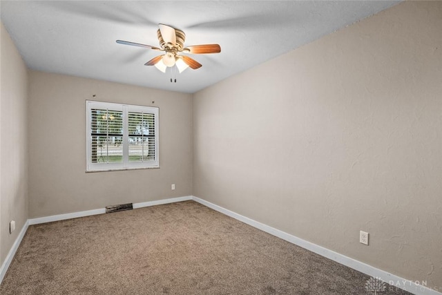 carpeted spare room featuring ceiling fan and baseboards