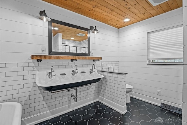 bathroom with toilet, wooden ceiling, a sink, and tile patterned floors