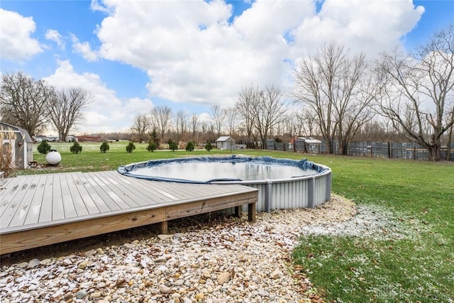 view of pool featuring a covered pool, a lawn, a wooden deck, and fence