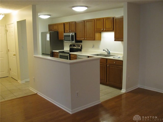 kitchen featuring kitchen peninsula, light hardwood / wood-style flooring, stainless steel appliances, and sink