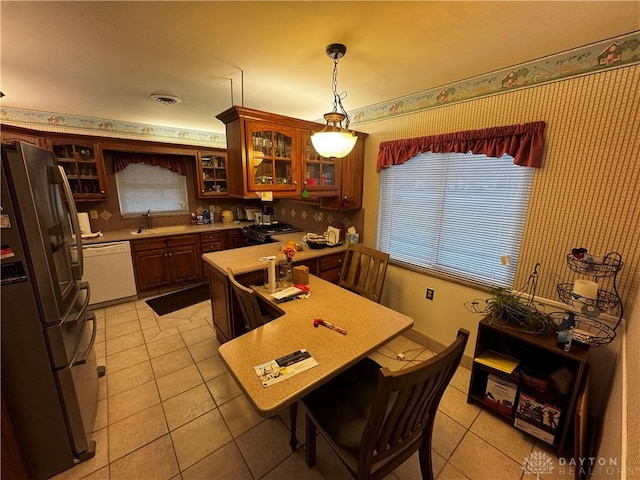 kitchen with stainless steel refrigerator, black stove, sink, white dishwasher, and pendant lighting