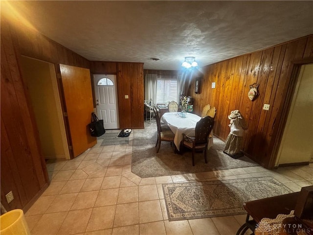 dining area with light tile patterned floors, a textured ceiling, and wooden walls