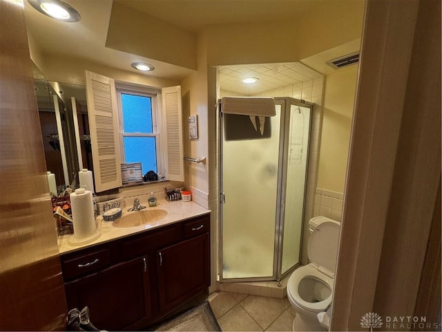 bathroom featuring tile patterned floors, vanity, toilet, and a shower with shower door