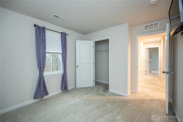 unfurnished bedroom with light carpet and a closet