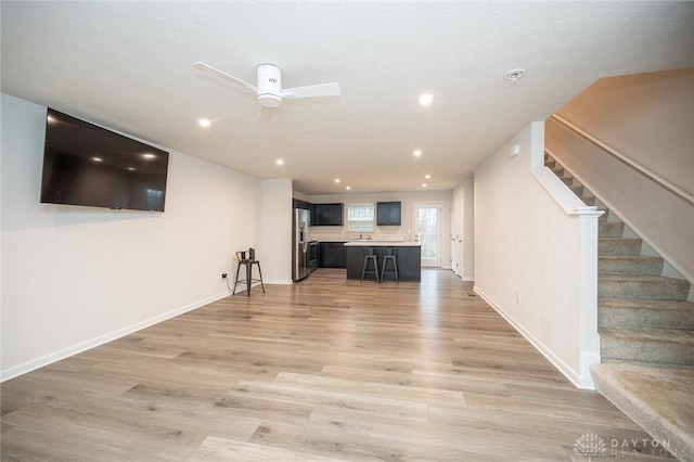 unfurnished living room with ceiling fan, light wood-type flooring, and sink