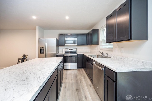 kitchen with light hardwood / wood-style floors, sink, stainless steel appliances, and a kitchen island