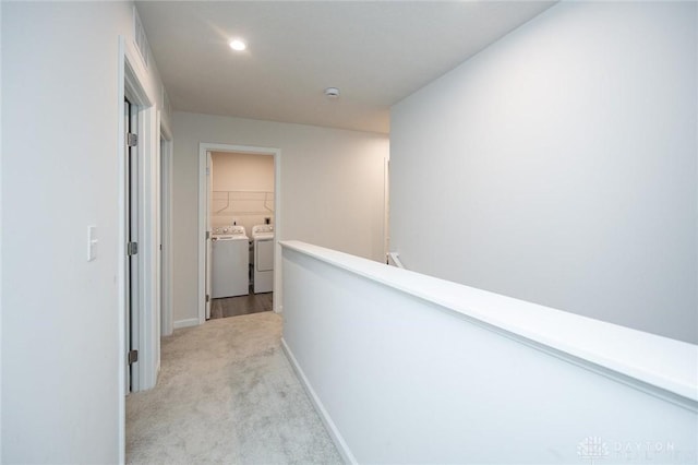 corridor with washing machine and clothes dryer and light colored carpet