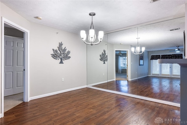 unfurnished dining area with a textured ceiling, ceiling fan with notable chandelier, and dark hardwood / wood-style floors