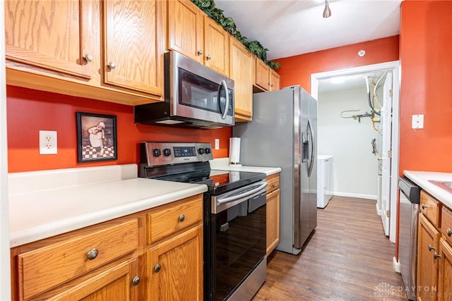 kitchen featuring a textured ceiling, stainless steel appliances, hardwood / wood-style flooring, and washing machine and clothes dryer