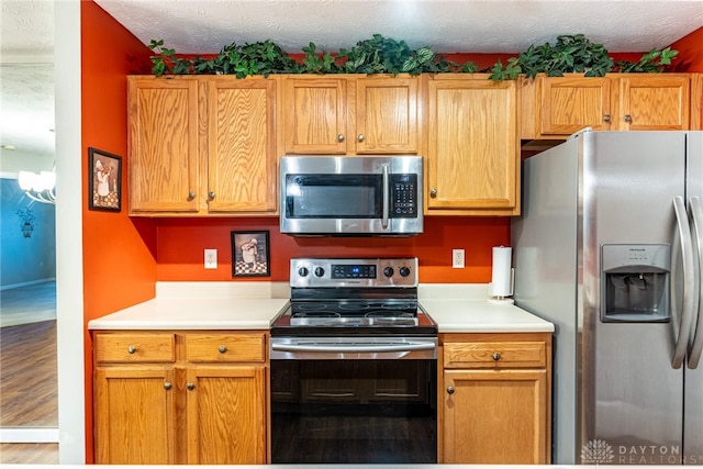 kitchen featuring a chandelier, appliances with stainless steel finishes, a textured ceiling, and wood-type flooring