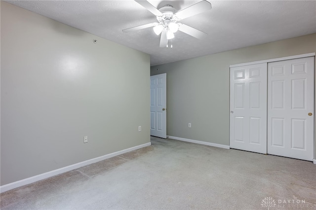 unfurnished bedroom featuring ceiling fan, light colored carpet, a textured ceiling, and a closet