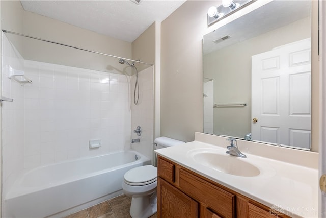 full bathroom featuring vanity, tile patterned floors, tiled shower / bath, toilet, and a textured ceiling