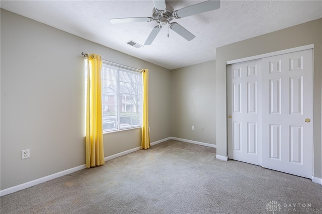 unfurnished bedroom with ceiling fan, light colored carpet, a textured ceiling, and a closet