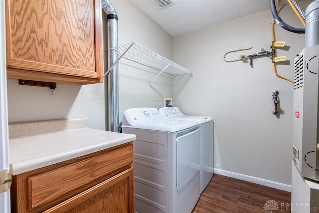 laundry area featuring washer and dryer, a textured ceiling, dark hardwood / wood-style floors, and cabinets