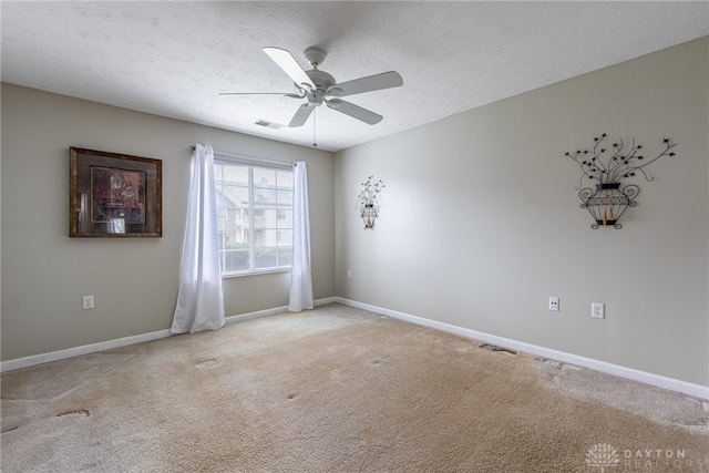 spare room with ceiling fan, light colored carpet, and a textured ceiling