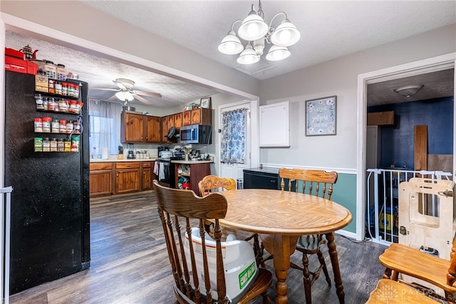 dining area featuring ceiling fan with notable chandelier, dark wood-type flooring, and a textured ceiling