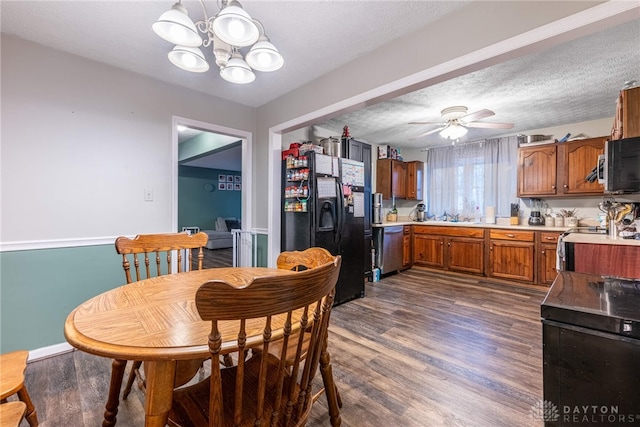 dining room with ceiling fan with notable chandelier, a textured ceiling, dark wood-type flooring, and sink