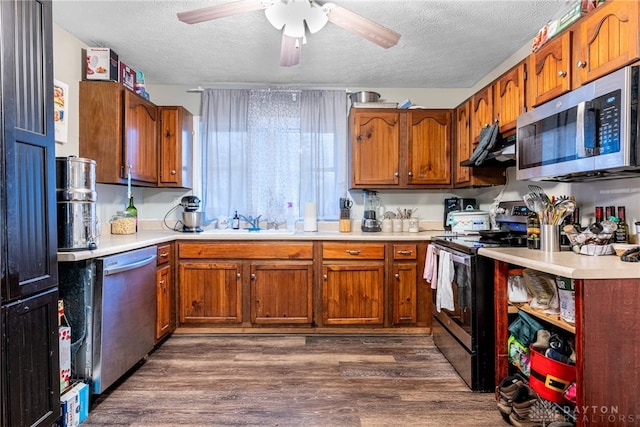 kitchen featuring appliances with stainless steel finishes, a textured ceiling, ceiling fan, dark wood-type flooring, and sink