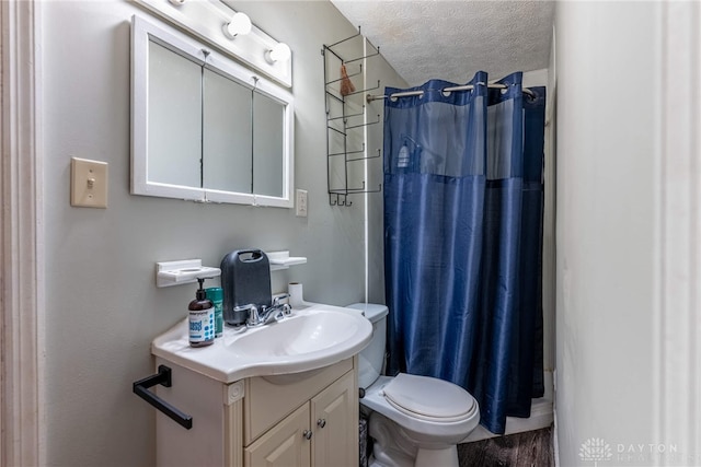 bathroom featuring vanity, toilet, a textured ceiling, and walk in shower