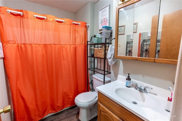 bathroom with vanity, a textured ceiling, hardwood / wood-style floors, toilet, and curtained shower