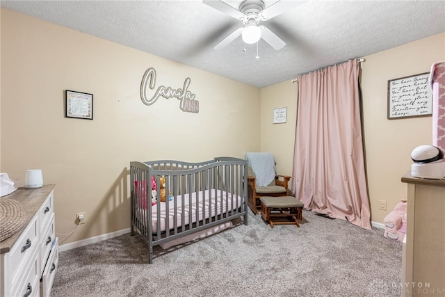 carpeted bedroom with a crib, a textured ceiling, and ceiling fan