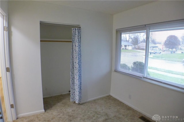 unfurnished bedroom with light carpet and a closet