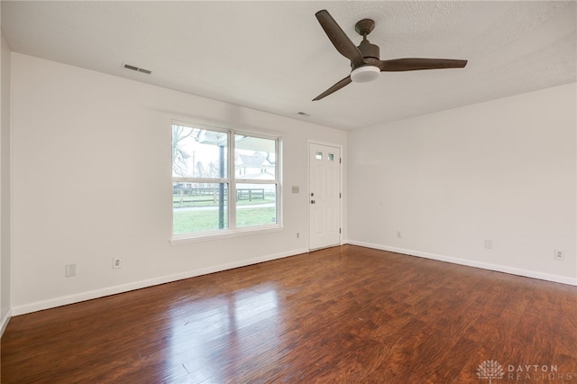 empty room featuring a textured ceiling, ceiling fan, and dark wood-type flooring