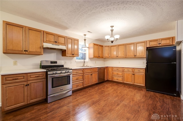 kitchen featuring dark wood-type flooring, sink, a textured ceiling, appliances with stainless steel finishes, and decorative light fixtures