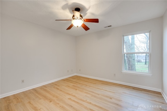 empty room featuring a textured ceiling, light wood-type flooring, and ceiling fan