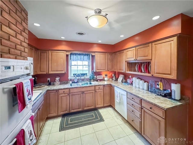 kitchen with light stone countertops, sink, light tile patterned flooring, and white appliances