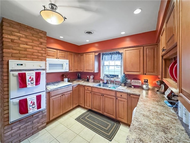 kitchen with sink, white appliances, light stone counters, and light tile patterned flooring