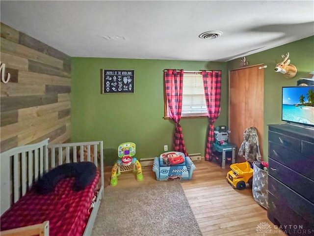 bedroom with light hardwood / wood-style flooring and a crib