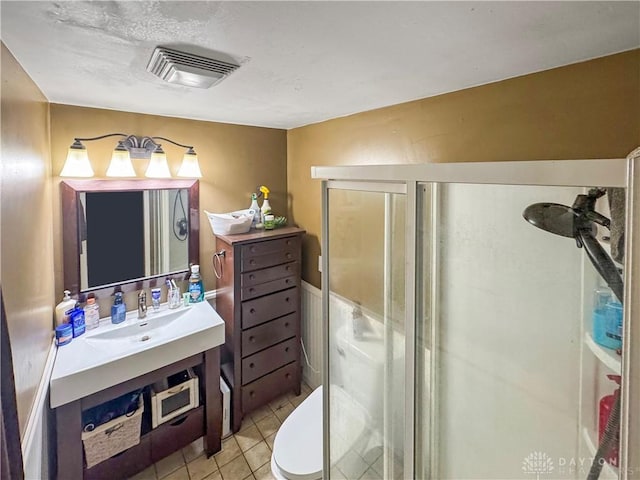 bathroom featuring tile patterned flooring, vanity, toilet, and a shower with door