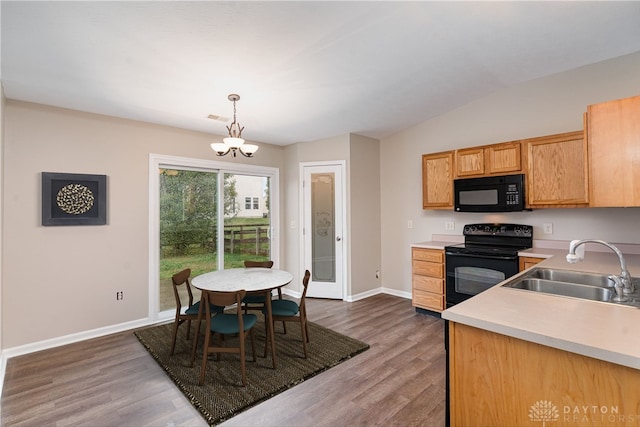 kitchen with pendant lighting, black appliances, sink, dark hardwood / wood-style flooring, and a chandelier