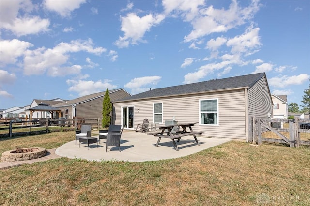 rear view of property with a lawn, a patio area, and a fire pit