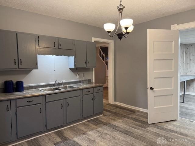 kitchen with gray cabinetry, sink, pendant lighting, and dark wood-type flooring